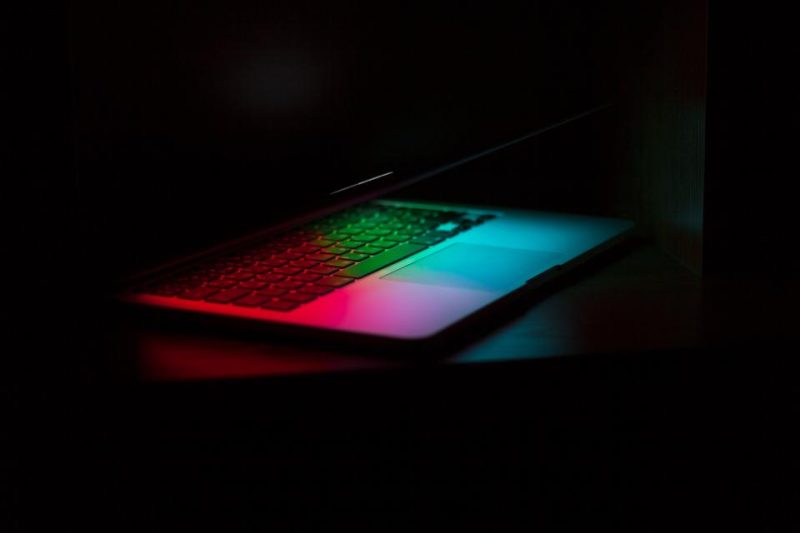 A laptop with a glowing keyboard in a dark room
