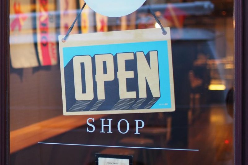 An Open sign hanging in the glass door of a small shop