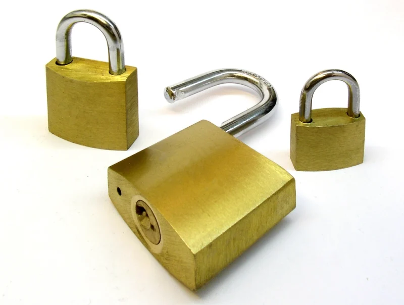 Three brass padlocks on a white background, one of them open