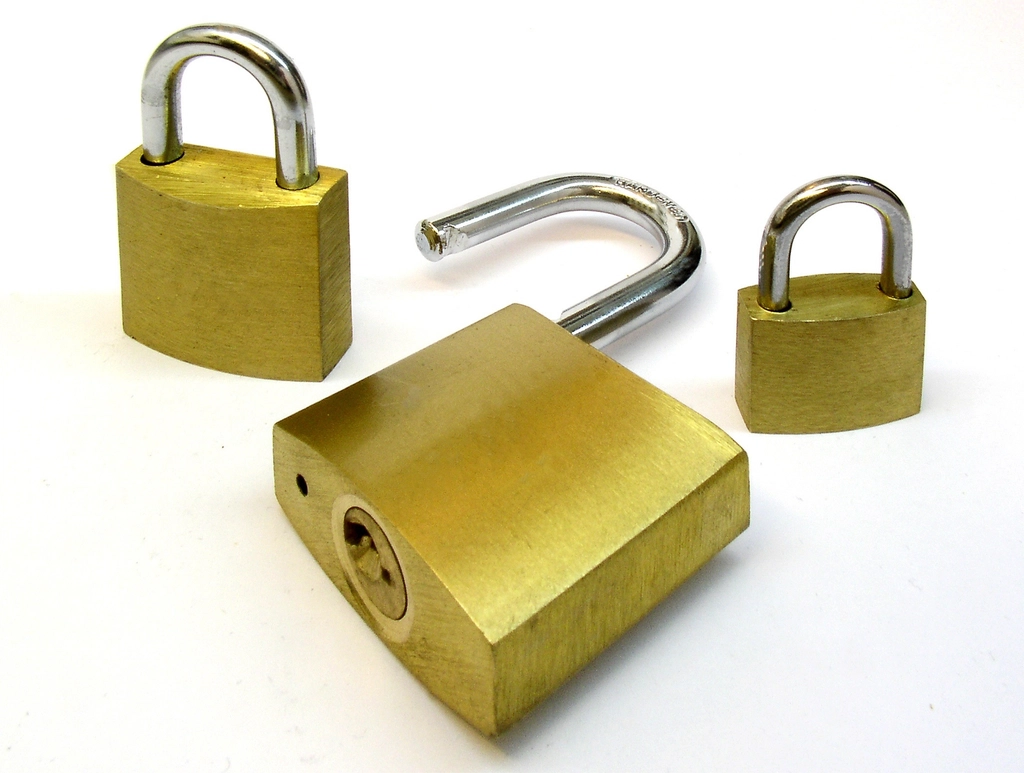 Three brass padlocks on a white background, one of them open