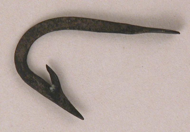 An old iron fish hook on a plain background