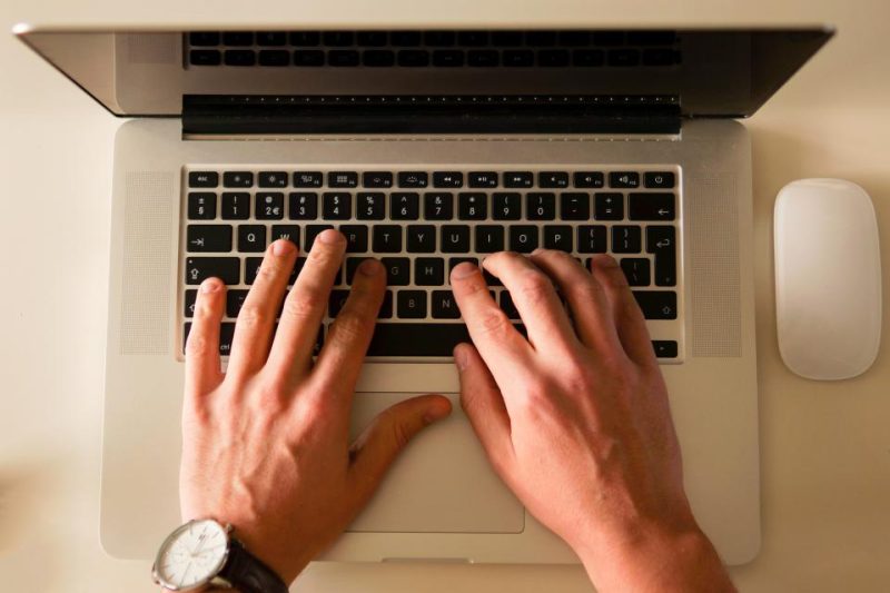Hands typing on a laptop keyboard, seen from above