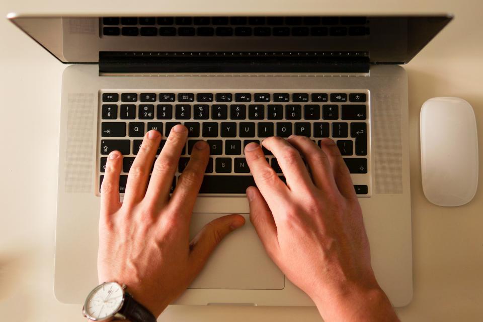 Hands typing on a laptop keyboard, seen from above